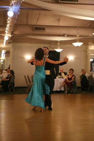 Woman in long blue dress dancing with man in black suit