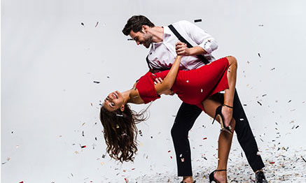Photo of woman in red dress being dipped by man in white shirt while dancing